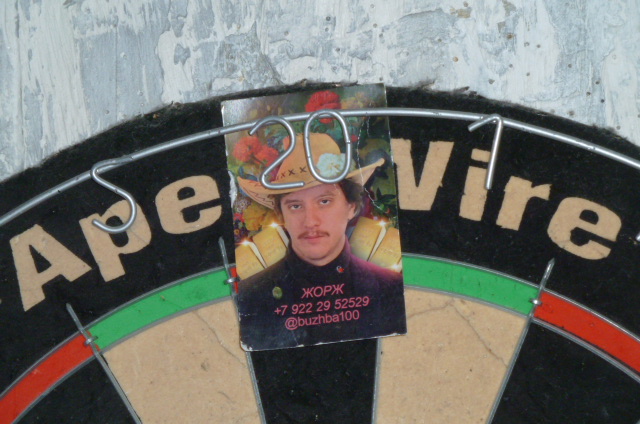 George Kornilov's business card clipped to a dartboard